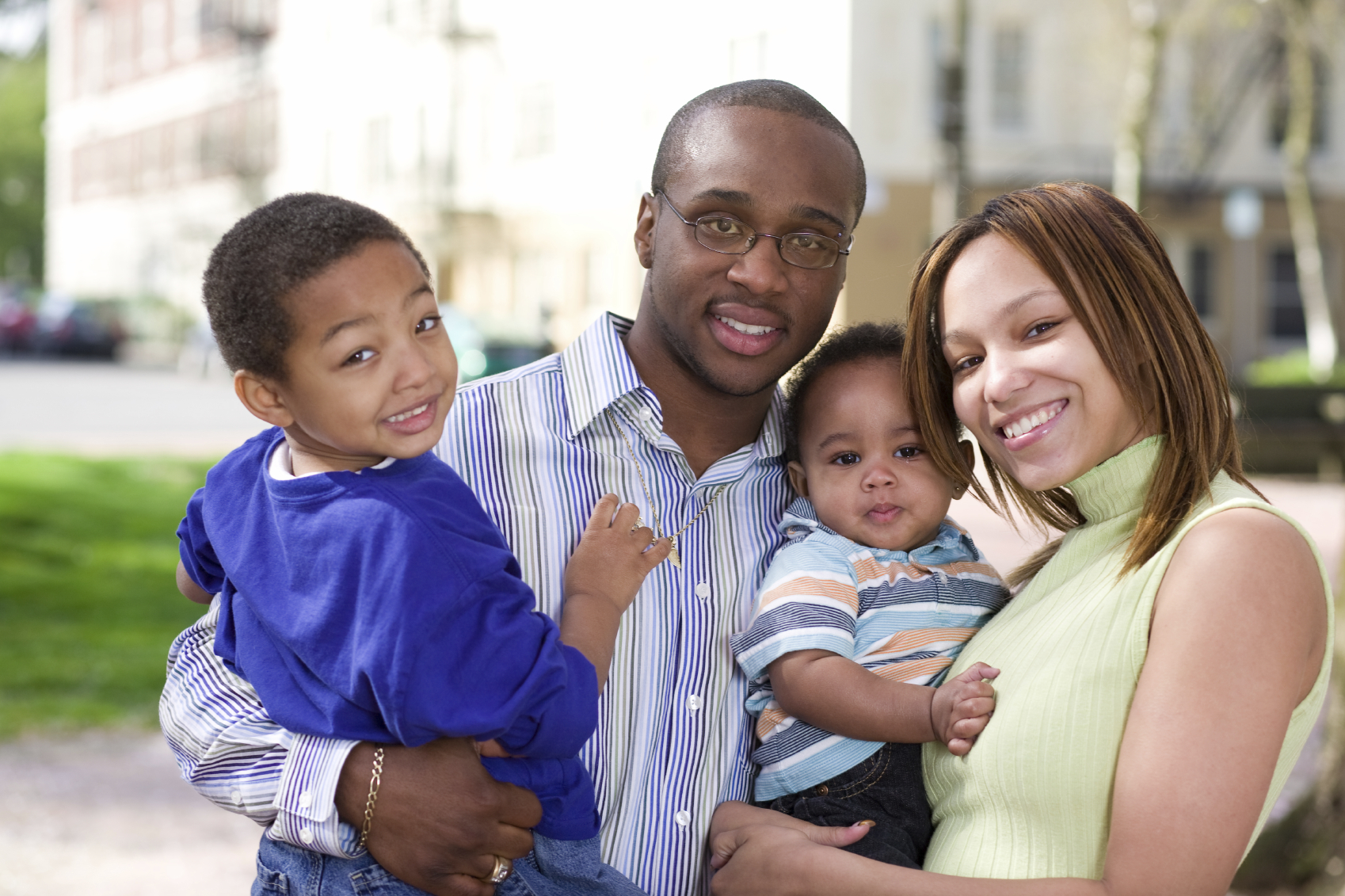 Family of four smiles outside together