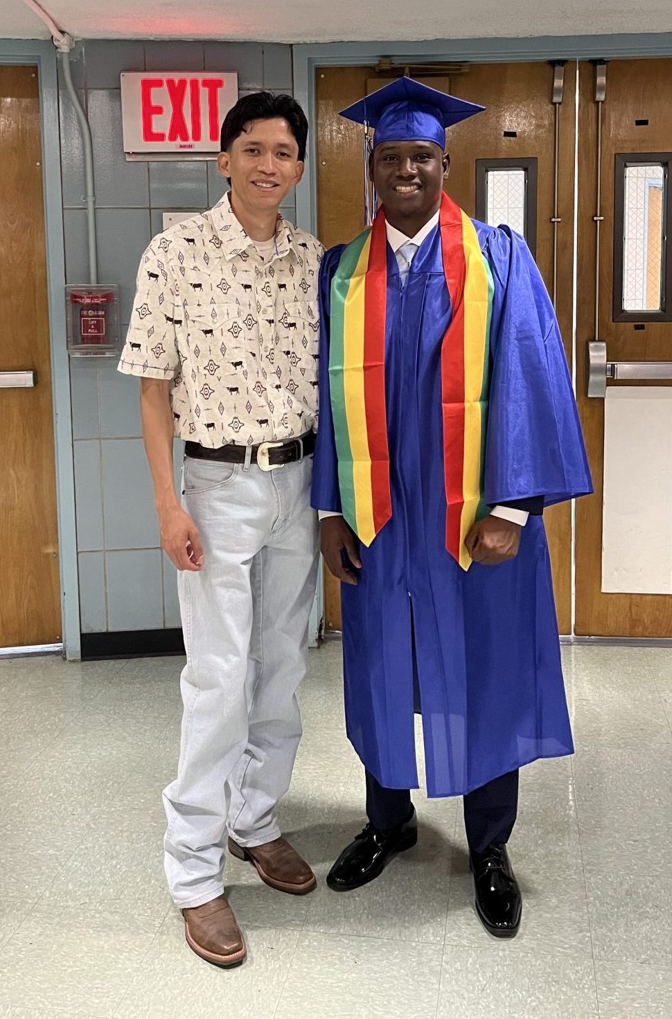 Roberto Quezada with a graduating student in their graduation robes