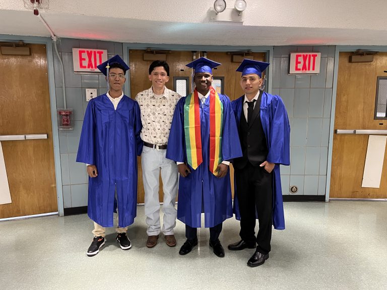 Roberto Quezada poses with three students from Queens Satellite High School on graduation day.