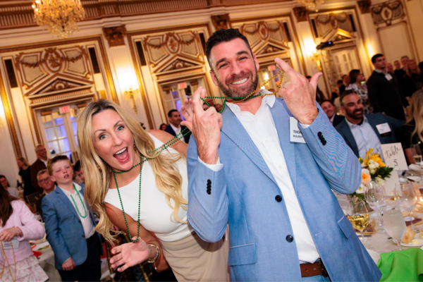 Two attendees smile with necklaces around their neck during the Heads and Tails game