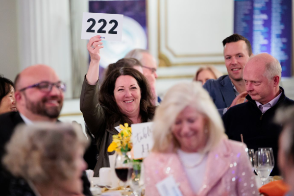 An attendee smiles as she holds her bid number up to donate to The Home